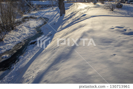 Snowy slope with long shadows and creek, winter minimalism, copy space 130713961