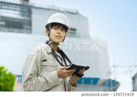 Young businessman in work clothes looking at a tablet at a construction site 130715429