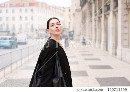 Young businesswoman in black coat standing on Young businesswoman in black coat standing on 130715599