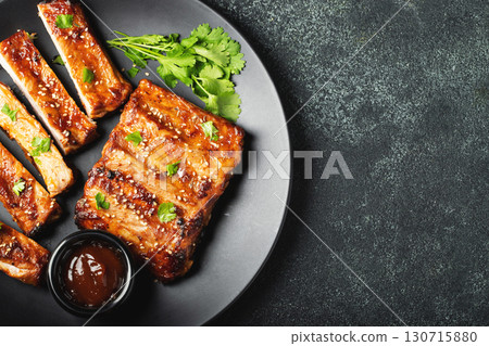 Hot grilled spare ribs from a summer BBQ served on a plate with sauce. Top view. Copy space 130715880