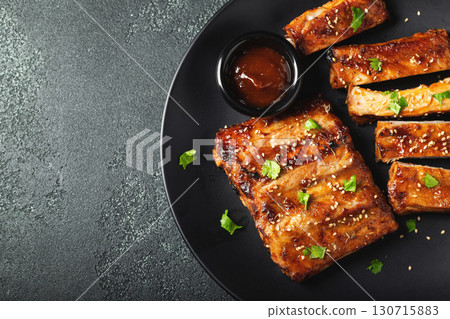 Hot grilled spare ribs from a summer BBQ served on a plate with sauce. Top view. Copy space Hot grilled spare ribs from a summer BBQ served on a plate with sauce. Top view. Copy space 130715883