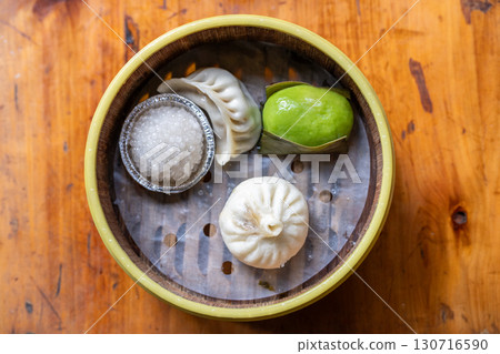 Assorted Asian Dumplings in Bamboo Basket on Wooden Table Assorted Asian Dumplings in Bamboo Basket on Wooden Table 130716590