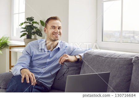 Portrait of a happy successful business man sitting on a sofa with his laptop computer Portrait of a happy successful business man sitting on a sofa with his laptop computer 130716684