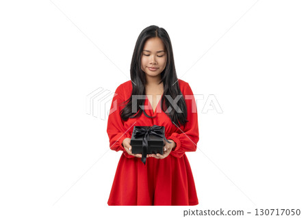 Young woman smiles gently while holding a gift box, isolated, PNG Young woman smiles gently while holding a gift box, isolated, PNG 130717050