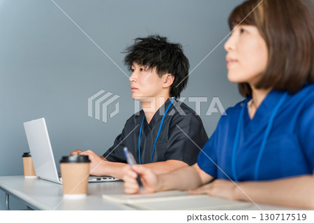 Male and female medical staff in scrubs attending medical conferences, study sessions, seminars, training sessions 130717519