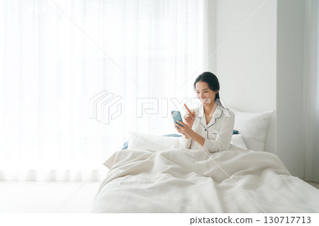 Woman operating smartphone in bed 130717713