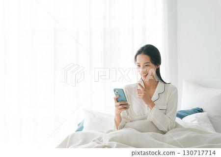 女人在床上操作智能手機 女人在床上操作智能手機 130717714