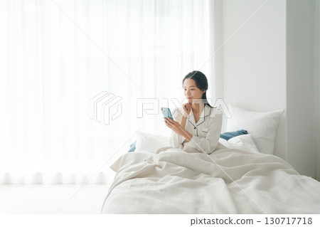 Woman operating smartphone in bed 130717718