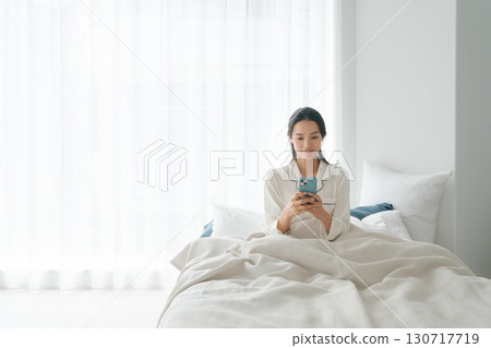 Woman operating smartphone in bed 130717719