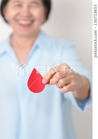Elderly woman in blue shirt with red Blood drop for World Diabetes Day, Blue November Health month, Diabetes awareness, Blood sugar check, Insulin, Glucose screening, blood donoo and Health checkup 130718655