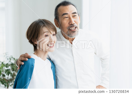 Senior couple looking outside by the window Senior couple looking outside by the window 130720834