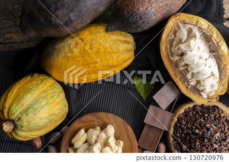 Close-up of Natural cocoa powder with brown cocoa beans and dry cacao pod  on a vintage wooden table. 130720976