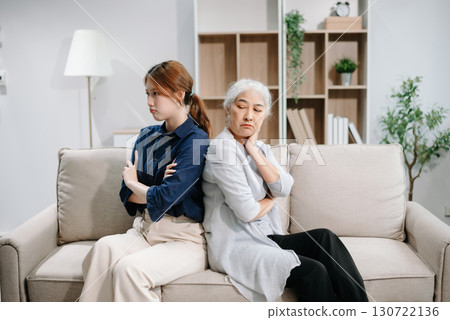 Mother and Daughter in Serious Disagreement emotional tension in silence on sofa at home, stressed after quarrel, ignoring each other 130722136