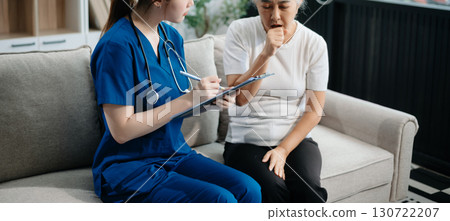 Asian caregiver doctor examine older patient woman therapist nurse at nursing home taking care of senior elderly woman sit on sofa.Medical service concept. Asian caregiver doctor examine older patient woman therapist nurse at nursing home taking care of senior elderly woman sit on sofa.Medical service concept. 130722207