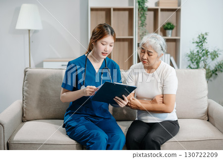 Asian caregiver doctor examine older patient woman therapist nurse at nursing home taking care of senior elderly woman sit on sofa.Medical service concept. Asian caregiver doctor examine older patient woman therapist nurse at nursing home taking care of senior elderly woman sit on sofa.Medical service concept. 130722209