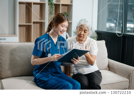 Asian caregiver doctor examine older patient woman therapist nurse at nursing home taking care of senior elderly woman sit on sofa.Medical service concept. 130722210