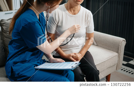 Asian caregiver doctor examine older patient woman therapist nurse at nursing home taking care of senior elderly woman sit on sofa.Medical service concept. Asian caregiver doctor examine older patient woman therapist nurse at nursing home taking care of senior elderly woman sit on sofa.Medical service concept. 130722256