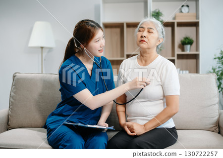 Asian caregiver doctor examine older patient woman therapist nurse at nursing home taking care of senior elderly woman sit on sofa.Medical service concept. 130722257