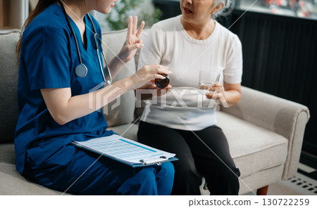 Asian caregiver doctor examine older patient woman therapist nurse at nursing home taking care of senior elderly woman sit on sofa.Medical service concept. 130722259
