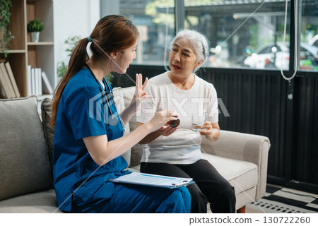 Asian caregiver doctor examine older patient woman therapist nurse at nursing home taking care of senior elderly woman sit on sofa.Medical service concept. 130722260