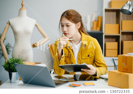 Young  woman prepare parcel box and standing check online orders for deliver to customer on tablet, laptop Shopping Online concept. 130722335