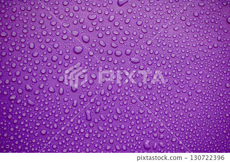 Purple toned background with uniform spread of round droplets creating a glossy wet effect. 130722396