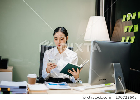 Young beautiful woman typing on tablet and laptop while sitting at the working 130722605