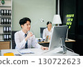 Two young Asian professionals engaged in teamwork and business discussions in modern office embodying corporate 130722623
