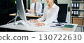Two young Asian professionals engaged in teamwork and business discussions in modern office embodying corporate 130722630