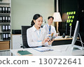 Two young Asian professionals engaged in teamwork and business discussions in modern office embodying corporate 130722641