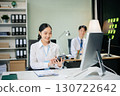 Two young Asian professionals engaged in teamwork and business discussions in modern office embodying corporate 130722642