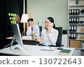 Two young Asian professionals engaged in teamwork and business discussions in modern office embodying corporate 130722643