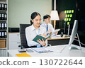 Two young Asian professionals engaged in teamwork and business discussions in modern office embodying corporate 130722644