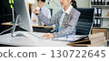 Two young Asian professionals engaged in teamwork and business discussions in modern office embodying corporate 130722645