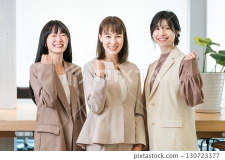 Smiling businesswomen posing in a row in the office Smiling businesswomen posing in a row in the office 130723377