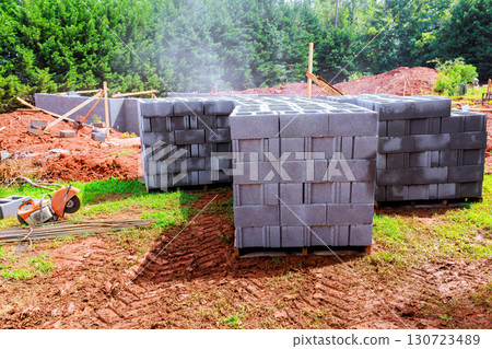 Heavy concrete blocks are stacked at construction site surrounded by trees under works during daytime. Heavy concrete blocks are stacked at construction site surrounded by trees under works during daytime. 130723489