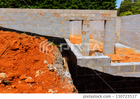 Construction workers lay groundwork for new homes, showcasing blocked walls rich red soil in works day 130723517