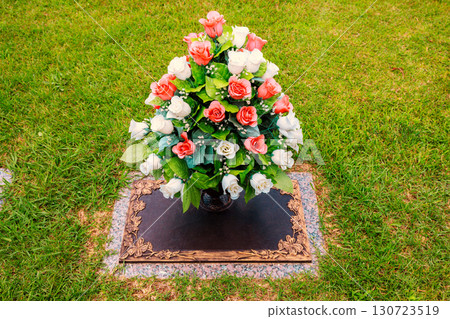 Arrangement of white, pink roses decorates gravestone in peaceful cemetery under farewell ceremony 130723519