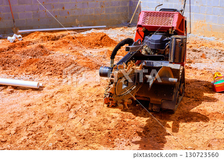 Heavy trench machinery operates on construction site, moving leveling dirt for new drainage system 130723560