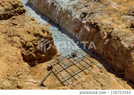 Excavation work reveals trench filled with gravel, ready for construction of building foundation on construction work Excavation work reveals trench filled with gravel, ready for construction of building foundation on construction work 130723583