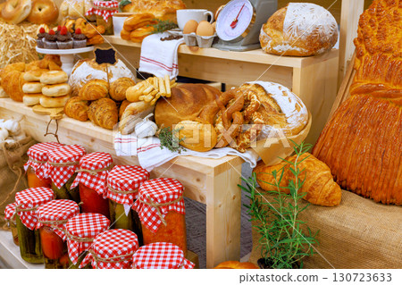 Freshly baked breads, pastries, jars of preserves beautifully arranged in market stall 130723633