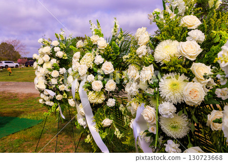 Elegant white floral displays are arranged beautifully, cemetery roses, greenery amid peaceful solemn funeral ceremony 130723668