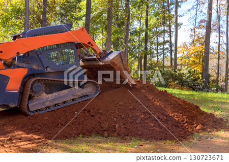 Heavy machinery is moving dirt in forested location on work day, reshaping landscape. Heavy machinery is moving dirt in forested location on work day, reshaping landscape. 130723671