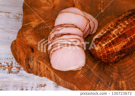 Slices of smoked meat rest on rustic wooden board, inviting for meal preparation or enjoying as snack. Slices of smoked meat rest on rustic wooden board, inviting for meal preparation or enjoying as snack. 130723672