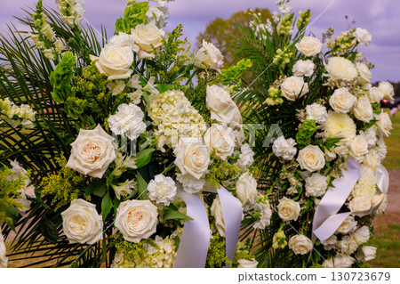 Two beautiful arrangements of white flowers at cemetery during are honorably placed on solemn funeral memorial site. Two beautiful arrangements of white flowers at cemetery during are honorably placed on solemn funeral memorial site. 130723679
