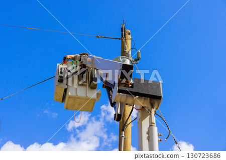 Maintenance crew uses bucket truck to check wires on tall utility pole under works day Maintenance crew uses bucket truck to check wires on tall utility pole under works day 130723686