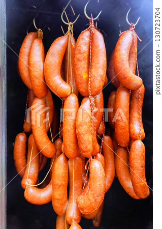 Unique assortment of smoked sausages hanging in market, artisanal food craftsmanship local food traditions Unique assortment of smoked sausages hanging in market, artisanal food craftsmanship local food traditions 130723704