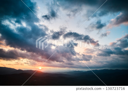Aerial view breathtaking sunset over forest. Sun's rays break through dramatic clouds. 130723716