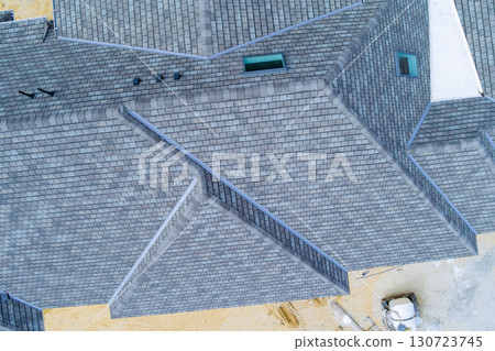 Overhead view of newly built house with gray slate roof, exposed construction materials in works day Overhead view of newly built house with gray slate roof, exposed construction materials in works day 130723745