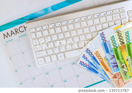 South Korean won cash lies next to calendar keyboard, indicating monthly budgeting activities in March. 130723767